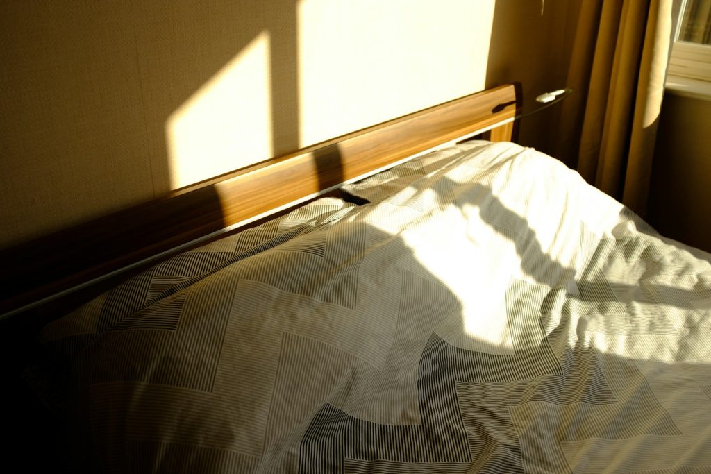 Cama iluminada por luz natural y textiles suaves
